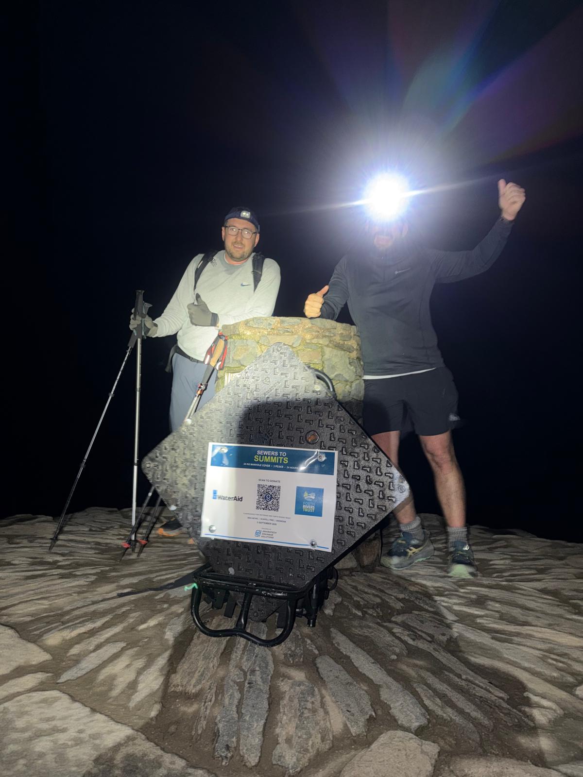 Sewers to Summits challenge manhole cover carrying the WaterAid and Forth Rivers Trust fundraising sign at a night-time summit